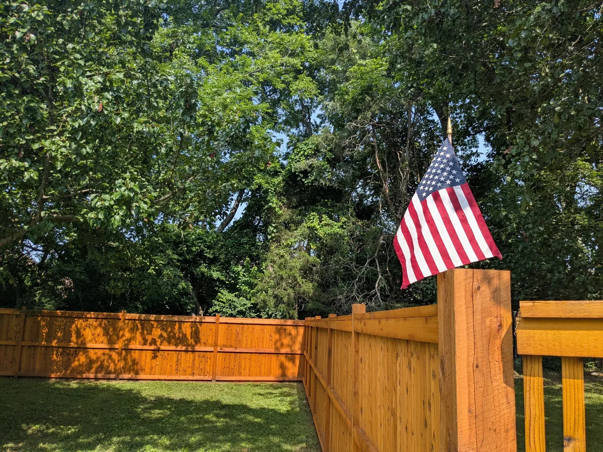 Freshly stained privacy fence with an American flag