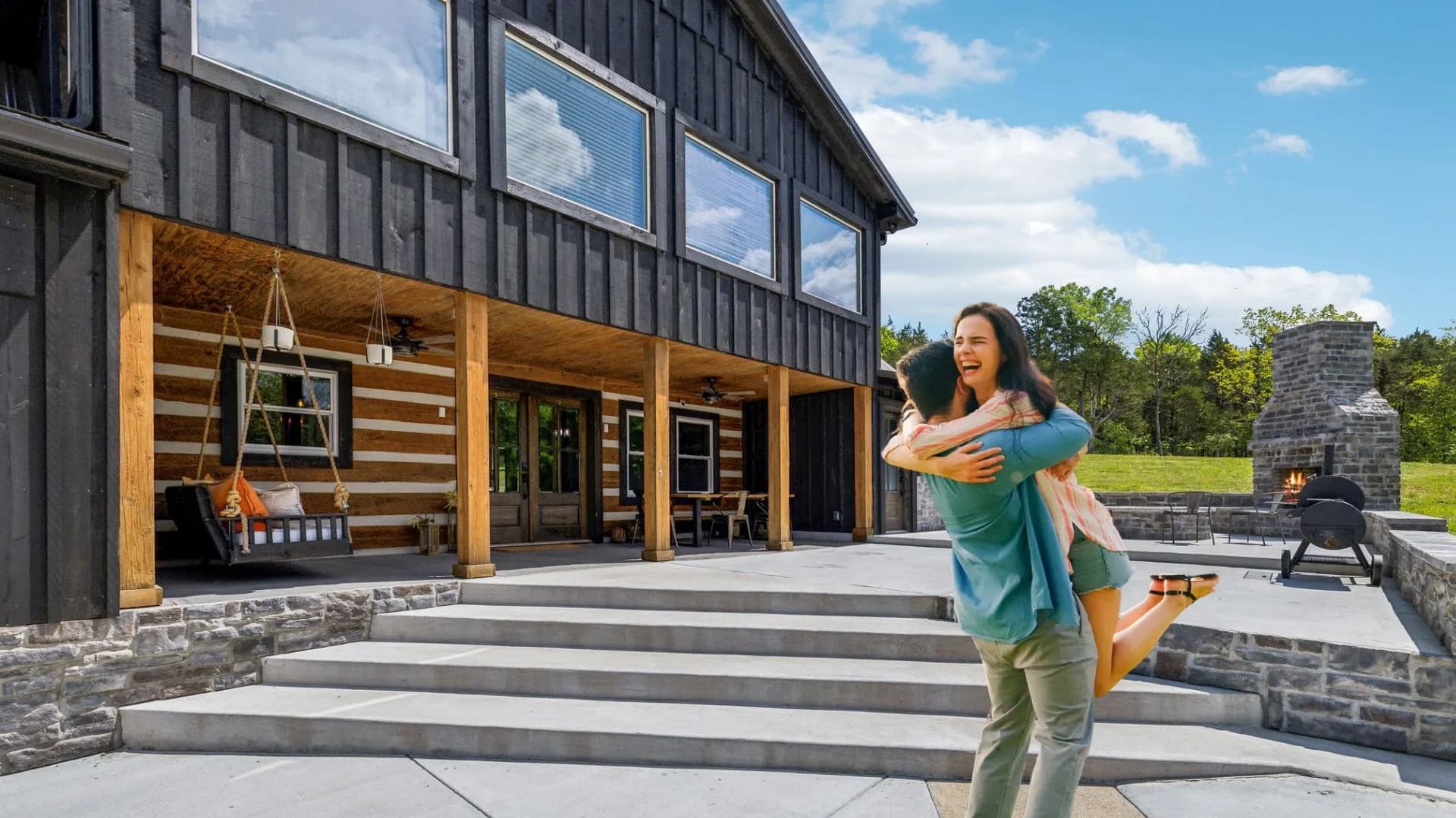 Happy homeowner in front of a stained log home